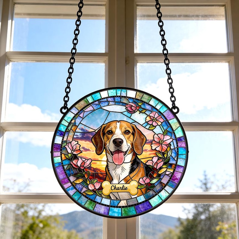 May include: A round, stained-glass window hanging featuring a beagle dog with a happy expression. The dog is surrounded by pink flowers and a colorful border. The name "Charlie" is on a bone-shaped plaque.