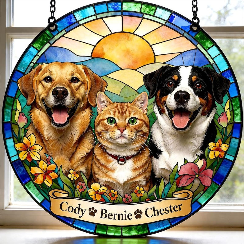 May include: Round stained glass art featuring a golden retriever, a tabby cat, and a black and white dog, with a sunny landscape background. The names "Cody", "Bernie", and "Chester" are on a banner. The artwork is framed with a blue and green border.