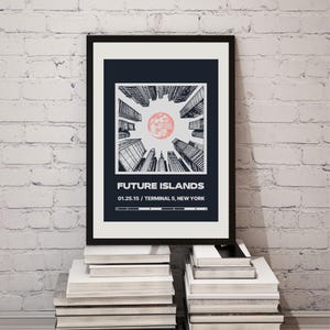 Può includere: Stampa artistica incorniciata raffigurante un paesaggio urbano stilizzato con un sole rosso. La stampa recita "FUTURE ISLANDS" con la data "01.25.15" e "TERMINAL 5, NEW YORK" sotto. La stampa è esposta su una pila di libri.