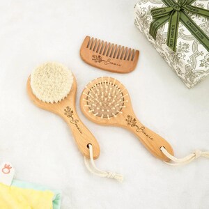 Könnte beinhalten: Ein hölzernes Haarpflegeset mit einer Rundbürste, einem kleinen Kamm und einer Bürste mit Naturborstenkopf. Das Set enthält eine Geschenkbox mit einem grünen Band mit der Aufschrift "Best Wishes". Die Holzartikel tragen das Wort "Bonnie" und ein Blumendesign.