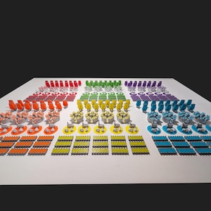 Op de afbeelding: Een kleurrijke set miniatuur spelstukken gerangschikt in een rasterpatroon op een wit oppervlak. De stukken zijn gemaakt van plastic en komen in verschillende kleuren, waaronder rood, oranje, geel, groen, blauw en paars. Elk stuk heeft een kleine, ronde basis en een grotere, rechthoekige bovenkant. De stukken zijn gerangschikt in een rasterpatroon, waarbij elke rij en kolom een ​​andere kleur bevat.