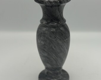 May include: A gray marble vase with a flared top and a rounded base. The vase has a smooth, polished finish and a swirling pattern of gray and white. The vase is approximately 6 inches tall.