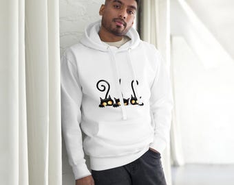 May include: White hoodie featuring a playful design of three black cats with yellow eyes. The cats are peeking out from the bottom of the hoodie, with whimsical curly tails. The hoodie has a front pocket and a drawstring hood.