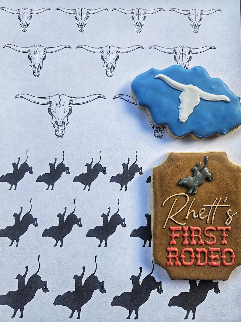 Puede incluir: Una galleta marr&oacute;n y beige decorada con el texto "Rhett's First Rodeo" en glaseado rojo y blanco. La galleta est&aacute; rodeada de un fondo blanco con un patr&oacute;n de cr&aacute;neos de toro negros y siluetas de vaqueros montando toros.