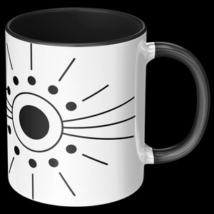 May include: White ceramic mug with a black interior and handle. The mug features a black and white graphic design of a central circle with radiating lines and dots. The handle is black.