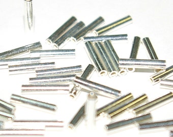 Può includere: Un mucchio di perline tubolari in metallo color argento. Le perline sono lunghe circa 1,2 cm e hanno una finitura liscia e lucida.