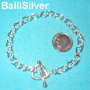 May include: A silver chain bracelet with a heart-shaped toggle clasp. The bracelet is about the size of a dime.