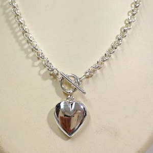 May include: A silver necklace with a heart pendant and a toggle clasp.