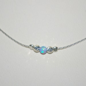 May include: A silver chain necklace with a single iridescent opal bead and two silver beads on either side.