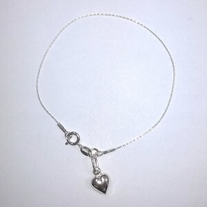 May include: A silver chain bracelet with a small heart charm.