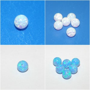 May include: A close-up of a group of round, iridescent opal beads. The beads are white with a rainbow sheen. There are six beads in total, and they are arranged in a cluster.