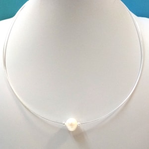 May include: A delicate silver chain necklace with a single white pearl pendant.
