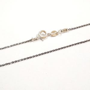 May include: A silver chain necklace with a lobster clasp. The chain is a delicate, thin, and box style.