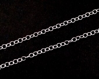 Puede incluir: Un collar de cadena de plata con un diseño delicado y enlazado. La cadena está colocada sobre un fondo negro.