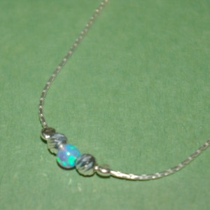 May include: A silver chain necklace with three beads, one of which is a blue-green opal.