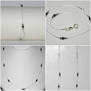 May include: A set of silver jewelry with black beads. The set includes a necklace, a bracelet, and a pair of earrings.