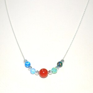 May include: A silver chain necklace with a variety of colored beads. The beads are blue, green, red, and black. The necklace is on a white background.