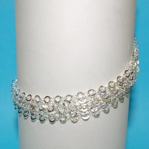 May include: Silver chain bracelet with multiple layers of small, linked circles.