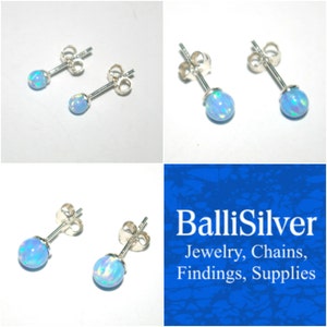 May include: A pair of silver stud earrings with a light blue opal stone. The earrings are set on a silver post with a butterfly back.