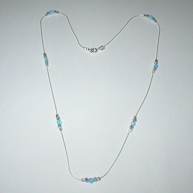 May include: A silver chain necklace with light blue opal beads. The necklace has a lobster clasp closure.