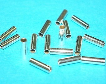 Può includere: Un gruppo di tubi di metallo argentato, alcuni con un leggero bagliore, sono sparsi su una superficie blu brillante. I tubi sono tutti della stessa dimensione e forma, e sembrano essere fatti di un metallo resistente.
