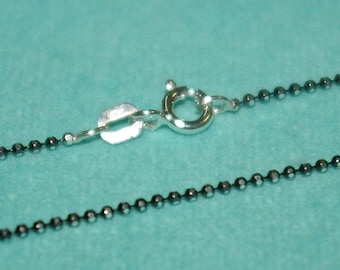 May include: A silver chain necklace with a black bead design. The chain has a lobster clasp closure.