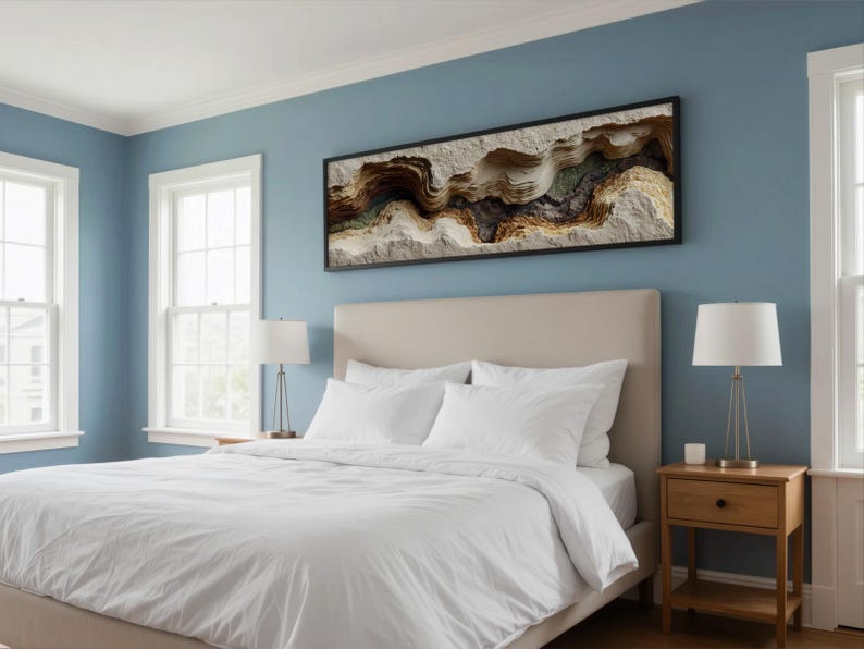 May include: A bedroom with a light blue wall, a bed with white bedding, and a framed abstract art piece. Two windows are on the left side of the bed. A nightstand with a lamp is on the right side of the bed.