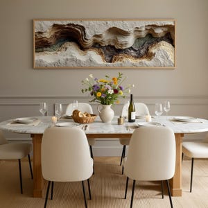 May include: A dining room scene featuring a marble-topped oval table set for a meal. Six cream-colored chairs with black legs surround the table. A framed artwork hangs above the table, and a vase of flowers sits in the center. Wine glasses and plates are set.