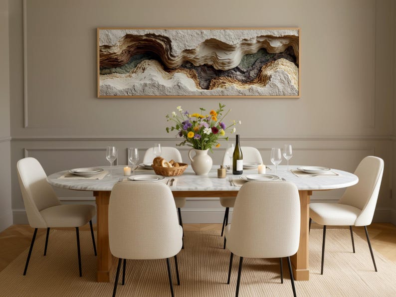 May include: A dining room scene featuring a marble-topped oval table set for a meal. Six cream-colored chairs with black legs surround the table. A framed artwork hangs above the table, and a vase of flowers sits in the center. Wine glasses and plates are set.