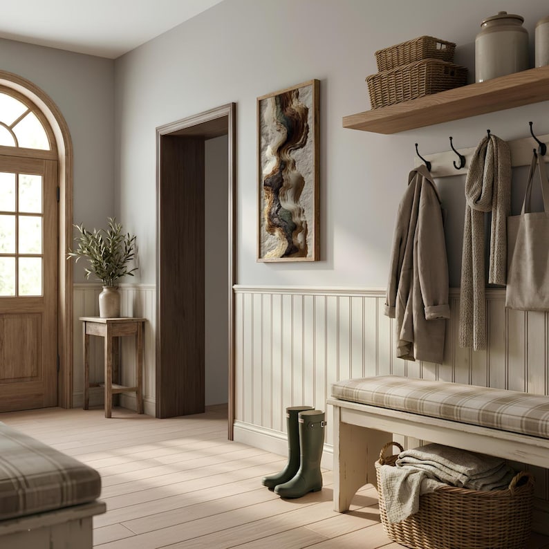May include: A neutral-toned entryway with a wooden door and floor. A framed abstract artwork hangs on the wall. A bench with a plaid cushion, a coat rack, and a basket are also present. Green rain boots stand near the bench.