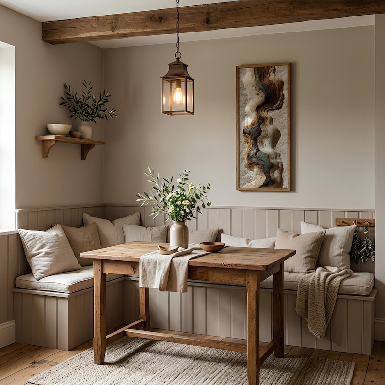 May include: A cozy dining area with a wooden table, benches, and a rug. A framed abstract artwork hangs on the wall. A lantern hangs above the table. Pillows and a vase with flowers add to the room's inviting atmosphere.