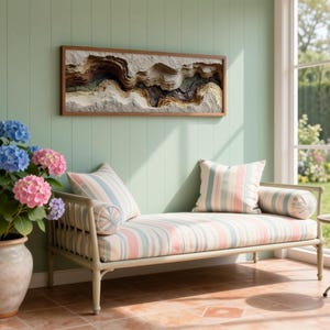 May include: A serene interior scene features a light green wall with a framed abstract art piece. A striped chaise lounge with pillows sits beneath the artwork. A potted hydrangea with blue and pink blooms adds a touch of color. A small side table holds a cup of tea.