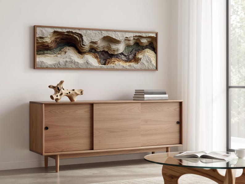 May include: A modern living room scene featuring a light wood sideboard with sliding doors, a round glass coffee table, and a framed abstract wall art piece. A decorative wooden sculpture and a stack of books are on the sideboard.