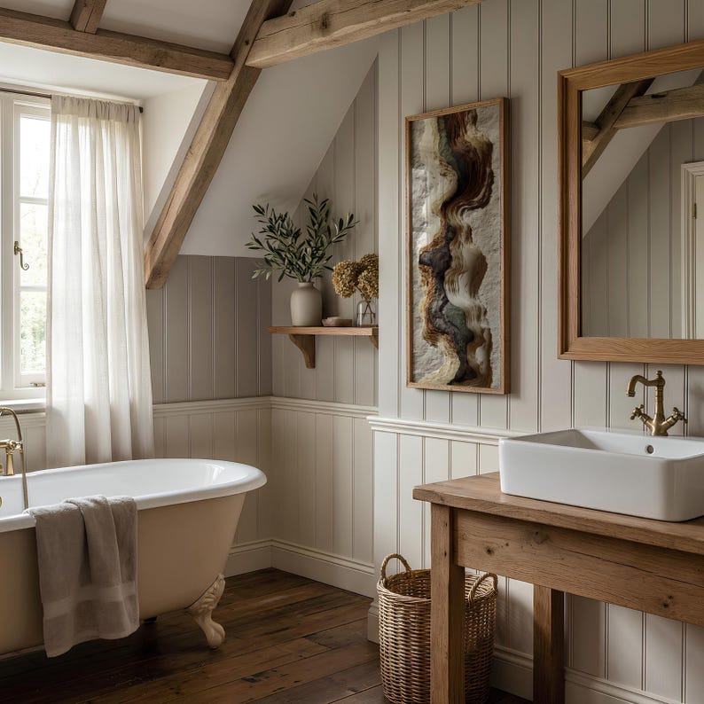 May include: A bathroom with a claw-foot bathtub, a wooden vanity with a white rectangular sink, and a framed artwork. The walls are painted in a neutral color, and the room has a rustic, spa-like feel. A window with sheer curtains is visible.