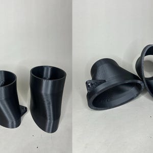May include: A set of four black 3D-printed automotive parts. Two are angled with a flange, and two are curved with a circular opening. The parts are made of a matte black plastic and are designed for a specific vehicle application.
