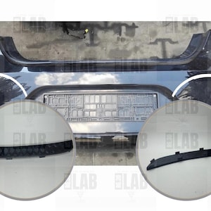 Può includere: Un paraurti nero per auto con un'area per la targa e due primi piani circolari. I primi piani mostrano finiture in plastica nera. Il paraurti ha luci integrate su ciascun lato.