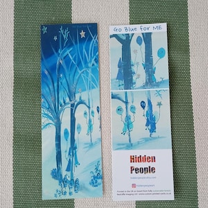 Op de afbeelding: Een blauwe en witte bladwijzer met een grillige illustratie van figuren in een besneeuwd bos. De bladwijzer heeft de tekst "Go Blue for ME" en "Hidden People" met een website-adres.
