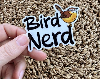 May include: A white sticker with black text that reads "Bird Nerd" and a cartoon image of a brown and yellow bird.
