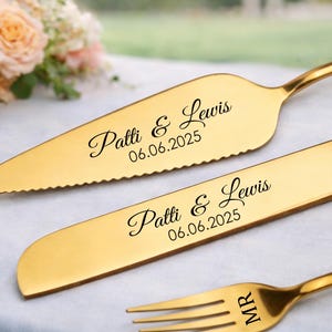 May include: Gold-colored wedding cake knife and server set with the names "Patti & Lewis" and the date "06.06.2025" engraved. A gold fork with "MR" engraved is also visible.