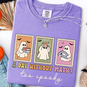 May include: A violet Comfort Colors long-sleeve shirt featuring a graphic with three ghost stamps. Each stamp has a ghost with books, a pi symbol, and a protractor. The text reads "A day without math? too spooky."