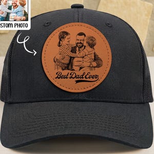 May include: A black baseball cap with a circular tan leather patch featuring a laser-engraved illustration of a parent hugging two children. The text "Best Dad Ever" is engraved in a cursive script at the bottom of the patch.
