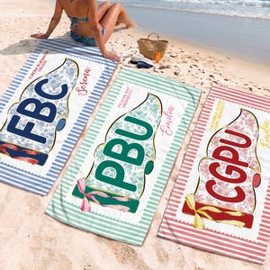 May include: Three personalized beach towels with ice cream cone designs are displayed on a sandy beach. Each towel features a different college abbreviation: FBC, PBU, and CGPU, along with a name. The towels have striped borders in blue, green, and red.