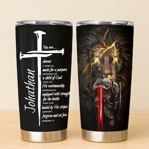 May include: Two stainless steel insulated tumblers. One features a white cross and the name "Johathan" with inspirational text on a black background. The other has a lion with a knight holding a red sword on a black background.