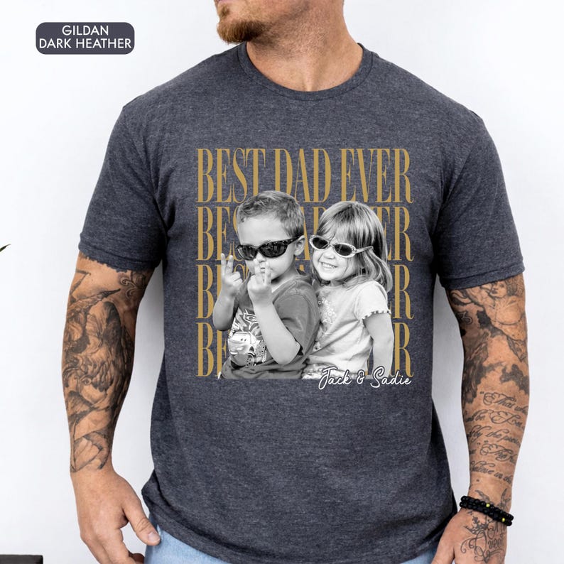 May include: Dark heather gray t-shirt with a graphic that says "BEST DAD EVER" in gold lettering. The graphic features a black and white photo of two children wearing sunglasses. The children's names, "Jack & Sadie", are printed below the photo.