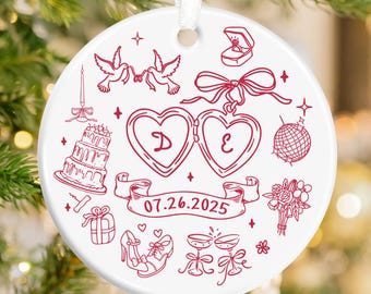 May include: A white ceramic ornament with a red wedding-themed design. The design includes doves, hearts, a cake, and the date 07.26.2025. A white ribbon is attached for hanging. Ideal for wedding gifts or holiday decor.