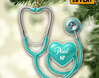 May include: A teal and silver stethoscope Christmas ornament. The ornament is shaped like a stethoscope with a heart-shaped chest piece. The name "Paul" and "NP" are written on the heart. The ornament is hanging from a gold string.