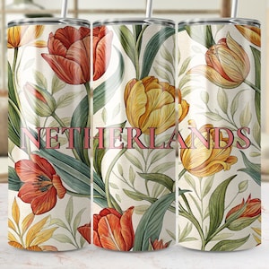 May include: A floral tumbler featuring a repeating pattern of orange and yellow tulips with green leaves against a cream background. The word "NETHERLANDS" is printed in pink. Includes a silver straw.