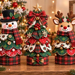 May include: Three decorative Christmas figures on a wooden surface: a snowman wearing a black top hat, a central Christmas tree topped with a gold star, and a reindeer with antlers. All feature red, green, and plaid fabric with small bells.