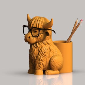 Op de afbeelding: Een bruin en oranje Highland Cow-figuur met een zwarte bril en een potloodhouder met potloden. De potloodhouder is oranje en de potloden zijn geel en roze.