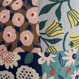 K&ouml;nnte beinhalten: Ein Textilstoff mit einem Patchwork-Design aus vier verschiedenen Blumenmustern. Die Abschnitte zeigen rosa Blumen auf braunem Grund, gelbe Tulpen auf hellblauem Grund, wei&szlig;e Blumen auf dunkelblauem Grund und rosa Blumen auf t&uuml;rkisfarbenem Grund.